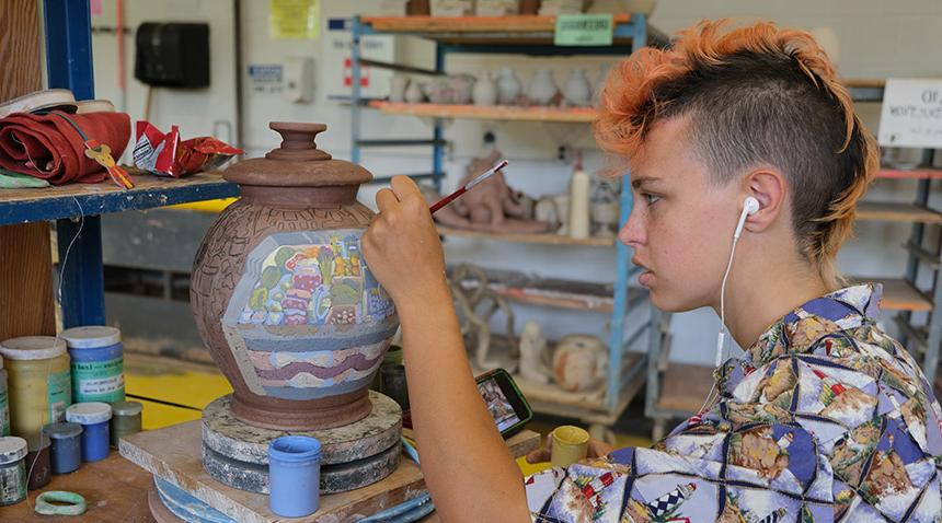 student painting a ceramic pot