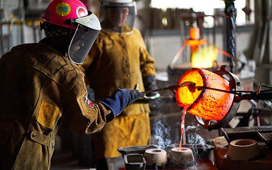 person pouring hot metal into molds